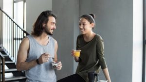 A happy young couple sharing a breakfast moment with juice and snacks indoors.